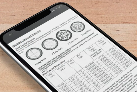 A smartphone on a wooden surface displays a document with diagrams of wheels and a detailed table listing specifications such as log count, size, and type.